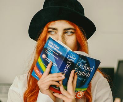 Girl is holding an Oxford Dictionary doing Intermediate English Vocabulary Exercises with answers